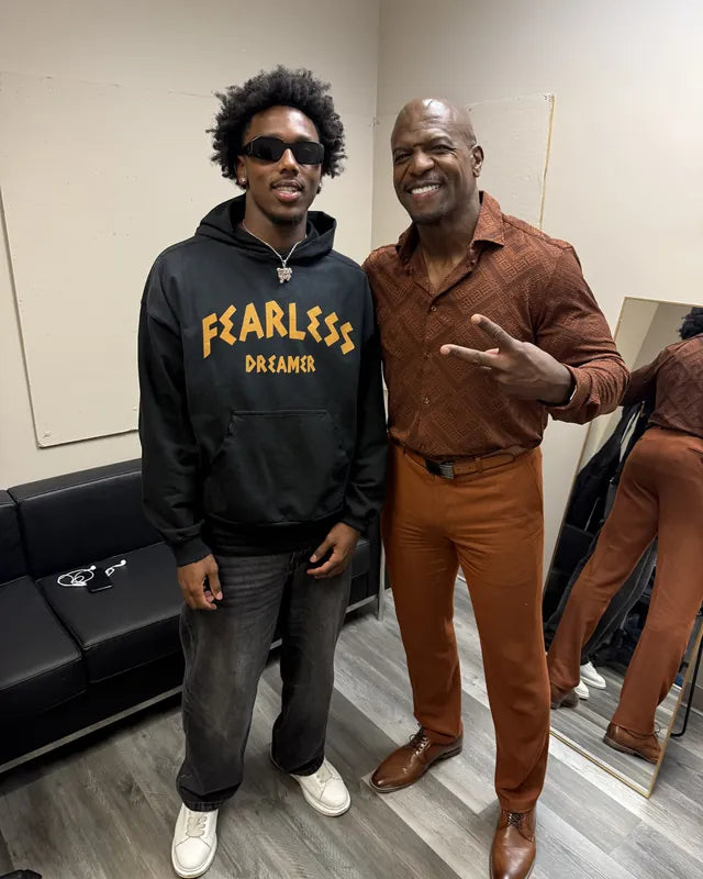 Two men posing together, one in a black Fearless Dreamer hoodie