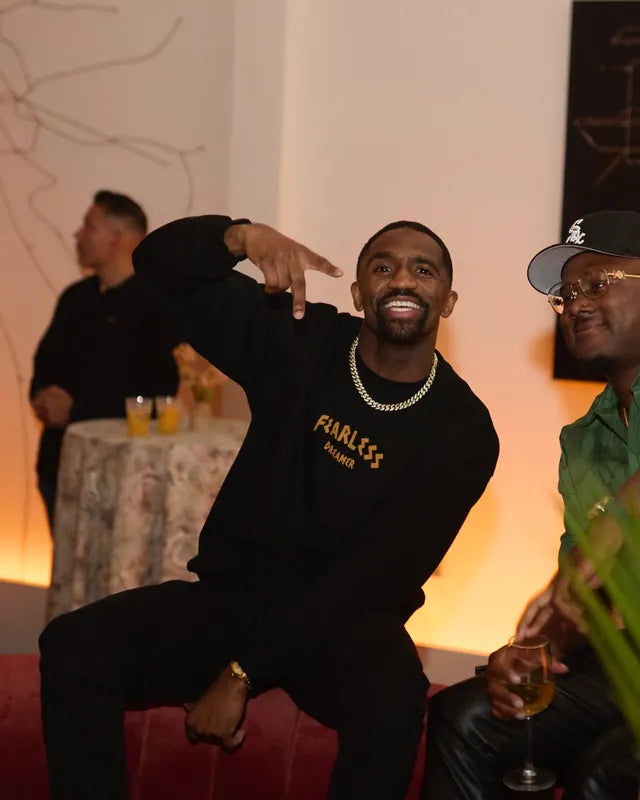 Man in a black Fearless Dreamer sweatshirt posing with friends at an event