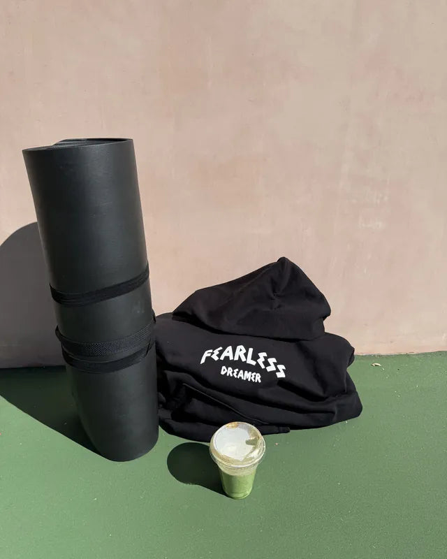 Black Fearless Dreamer hoodie next to a yoga mat and a green juice