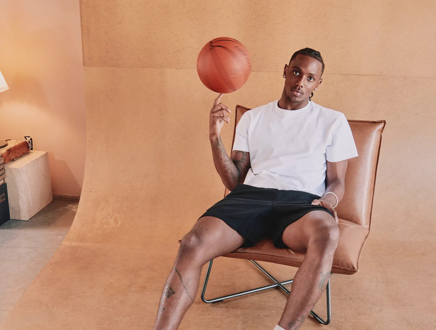 Model in a white tee spinning a basketball in a leather chair
