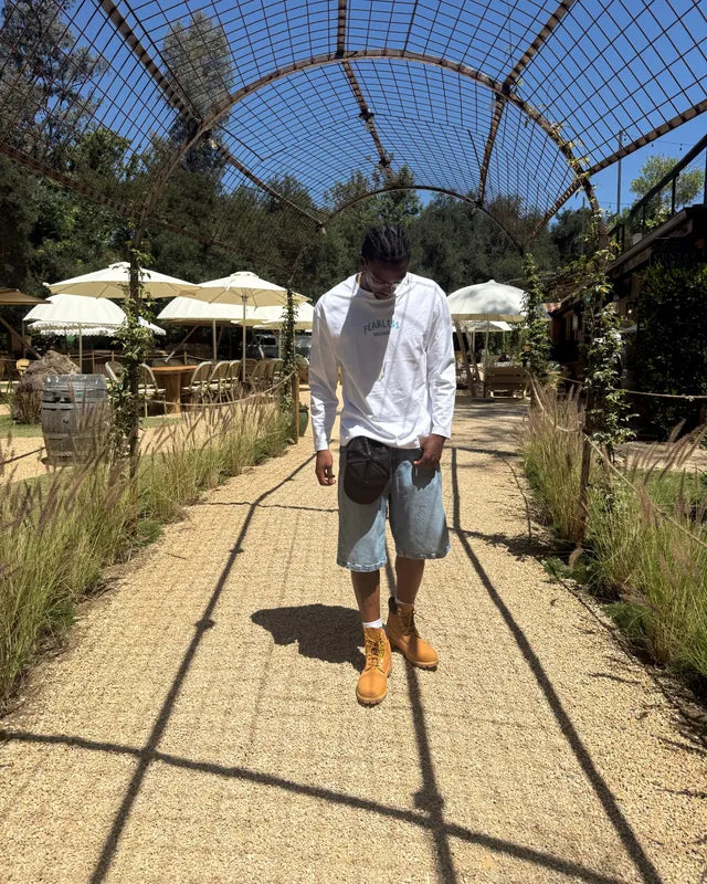 Man in a white Fearless Dreamer long sleeve tee walking under a garden arch