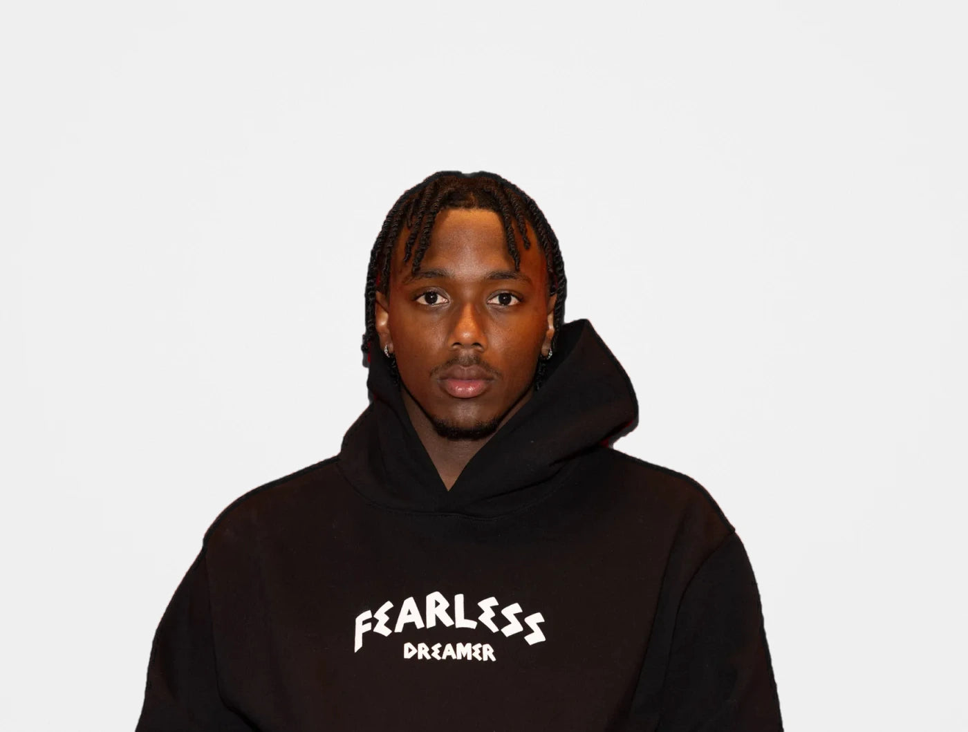 Model in a black Fearless Dreamer hoodie on a light grey background